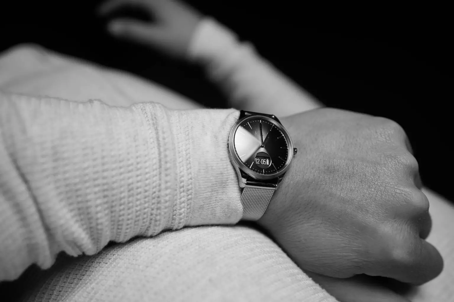 person wearing round silver-colored analog watch with link band